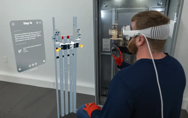 A man wearing an Apple Vision Pro next to a Siemens P5 power panel. He is looking at a digital overlay of BILT immersive instructions including a 3D rendering of the panel and a text window.